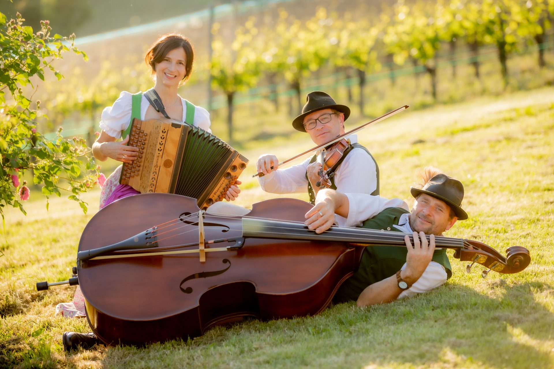 Trio entspannt im Gras mit Instrumenten